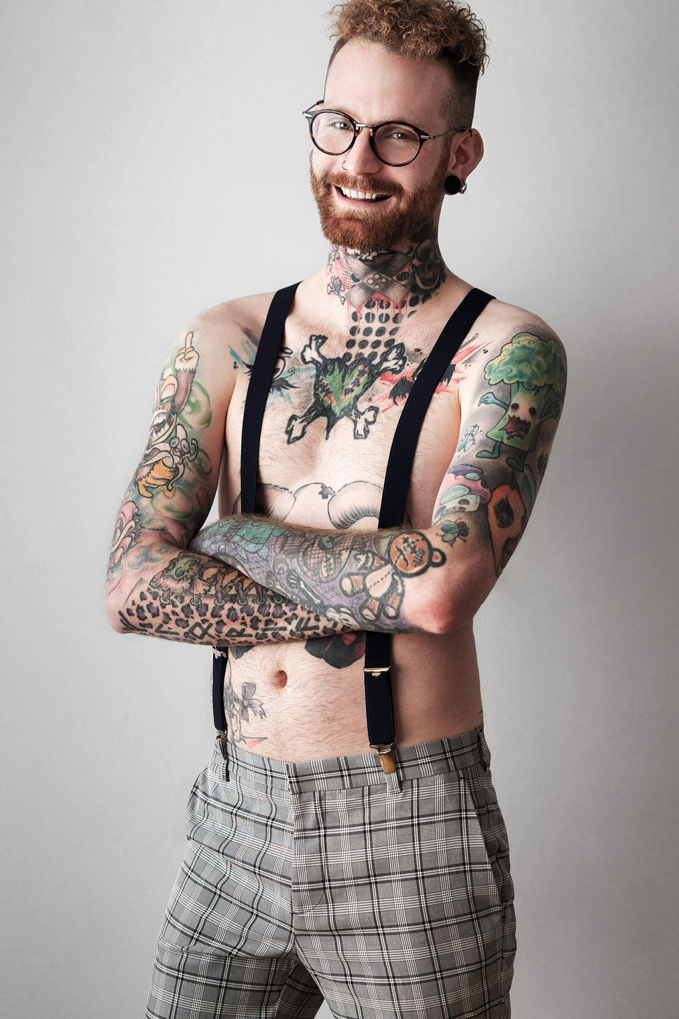 Portrait von tättoowiertem Mann mit Locken und Hosenträger